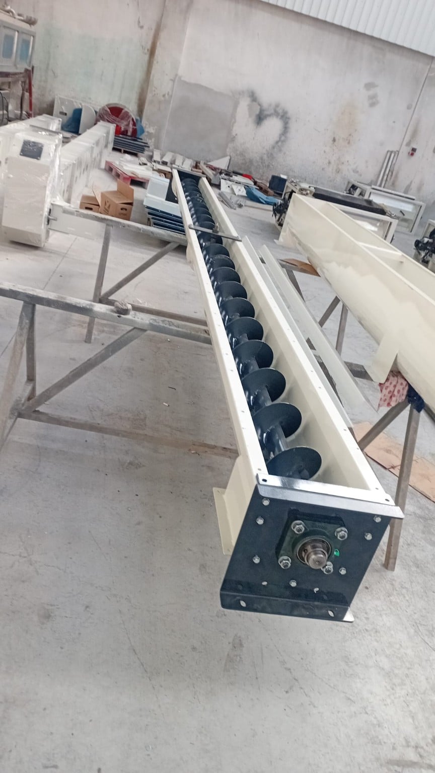 ADDAMS screw conveyor with exposed helical flight and end bearing in the workshop