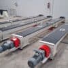 Four enclosed ADDAMS screw conveyors with geared motors in the workshop