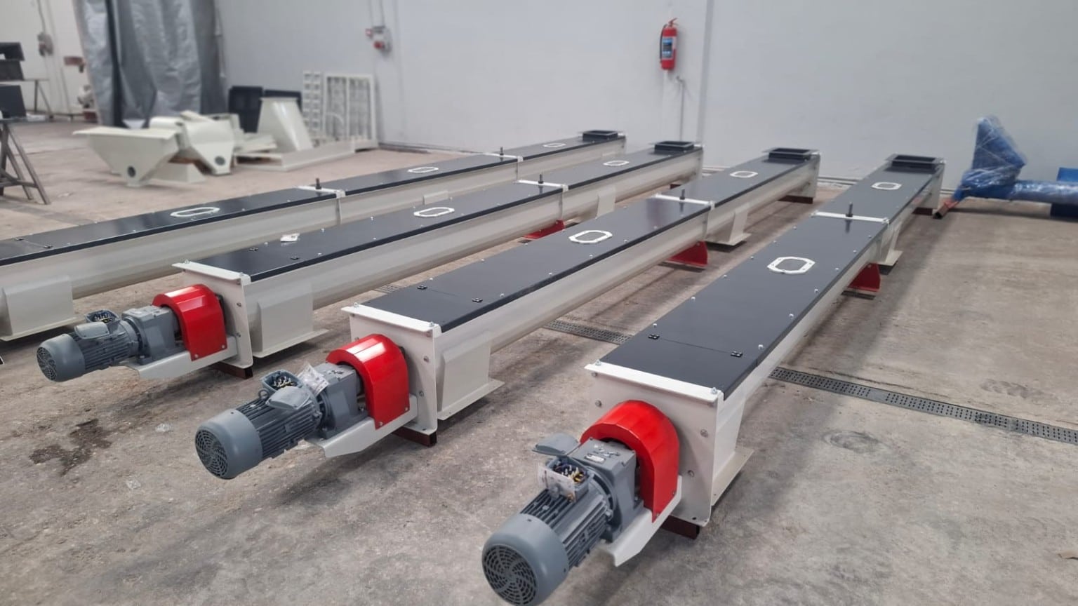 Four enclosed ADDAMS screw conveyors with geared motors in the workshop