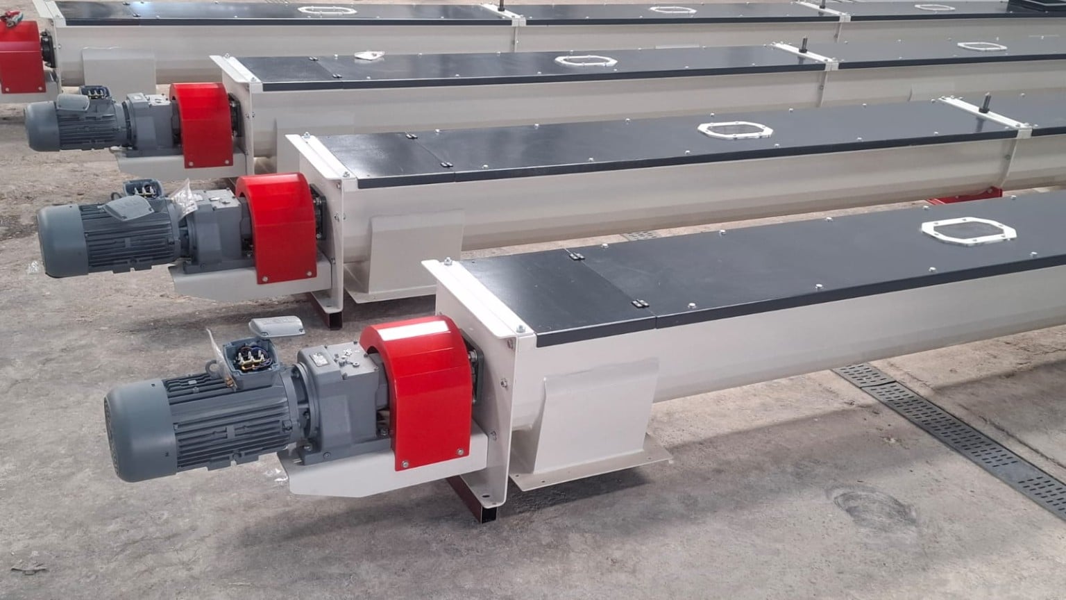 ADDAMS enclosed screw conveyors with red drive guards and geared motors