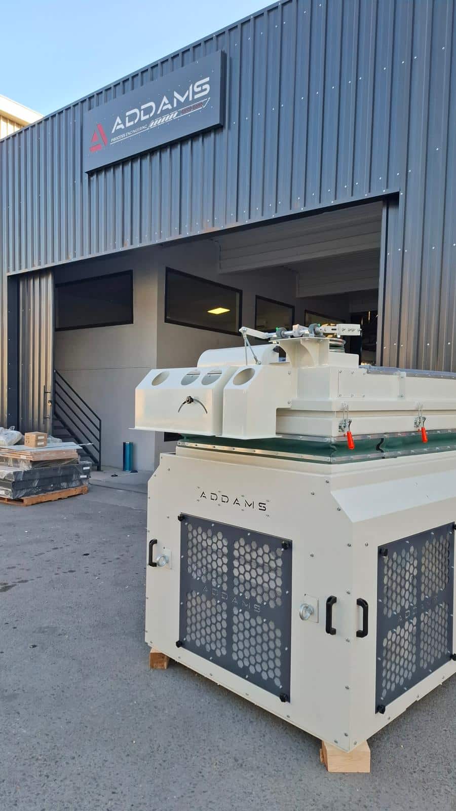 ADDAMS processing machine outside the factory entrance beneath the ADDAMS sign